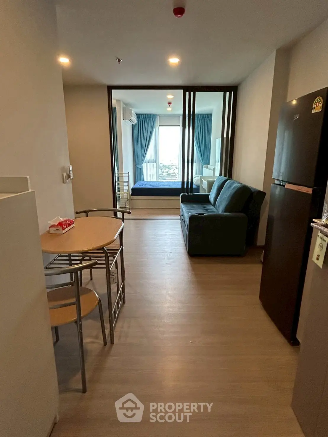 Modern apartment interior with open living and dining area, featuring sleek furniture and natural light.