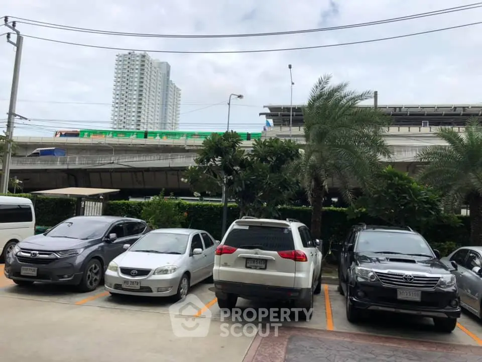 Urban parking lot with multiple cars and a cityscape backdrop, ideal for city living convenience.