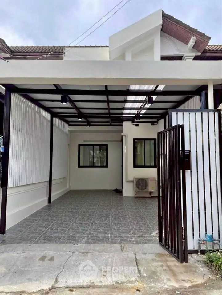 Modern carport with tiled flooring and sleek metal gate in residential area.