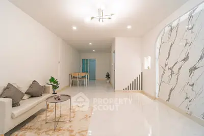 Spacious modern living room with elegant marble accents and cozy seating area.