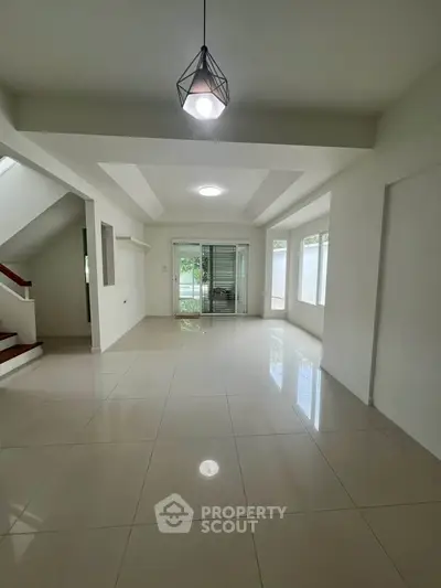 Spacious open-plan living area with modern lighting and large windows.