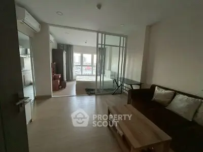 Spacious living room with modern furniture and glass partition in a stylish apartment.