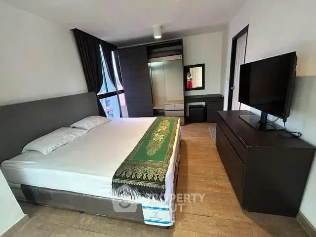 Spacious bedroom with modern furnishings and large window for natural light.