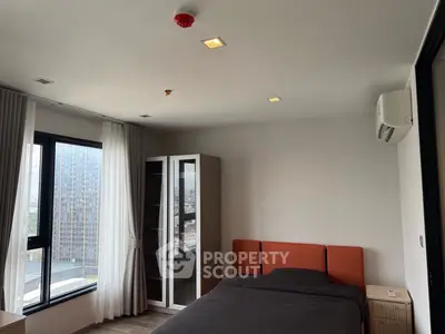 Modern bedroom with city view, featuring sleek furniture and large windows for natural light.