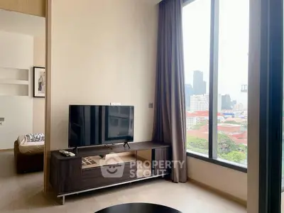Modern living room with large window offering stunning city view, featuring sleek TV stand and cozy decor.