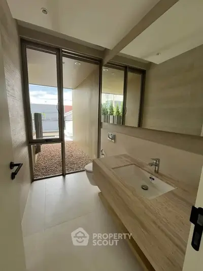 Modern bathroom with sleek design and large windows offering natural light and outdoor view.