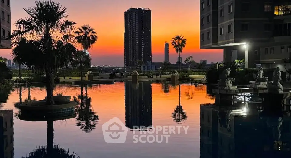Stunning sunset view over a luxurious apartment pool with palm trees and city skyline.