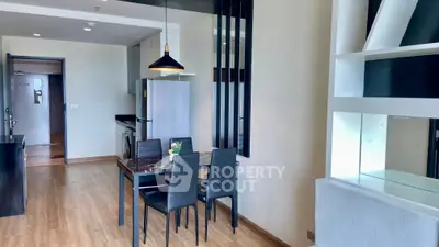 Modern dining area with sleek black table and chairs, adjacent to a contemporary kitchen.