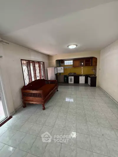 Spacious open-layout kitchen with vintage wooden sofa and tiled flooring.
