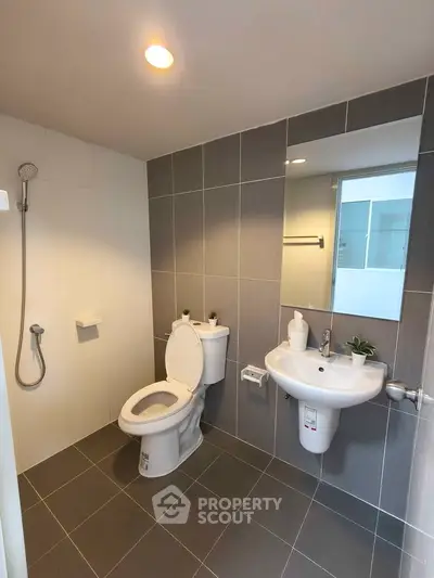 Modern bathroom with sleek gray tiles and contemporary fixtures in a stylish apartment.