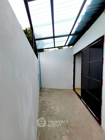 Modern outdoor space with sleek glass door and covered roof, ideal for versatile use.