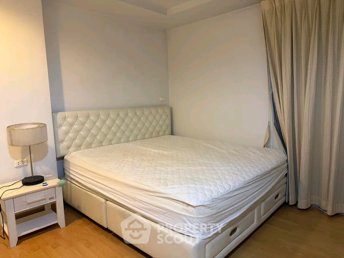 Spacious bedroom with elegant white bed and stylish lamp, perfect for relaxation and comfort.