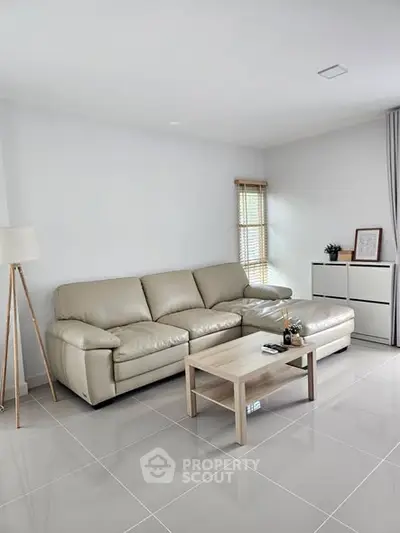 Modern living room with beige sofa, sleek coffee table, and minimalist decor.