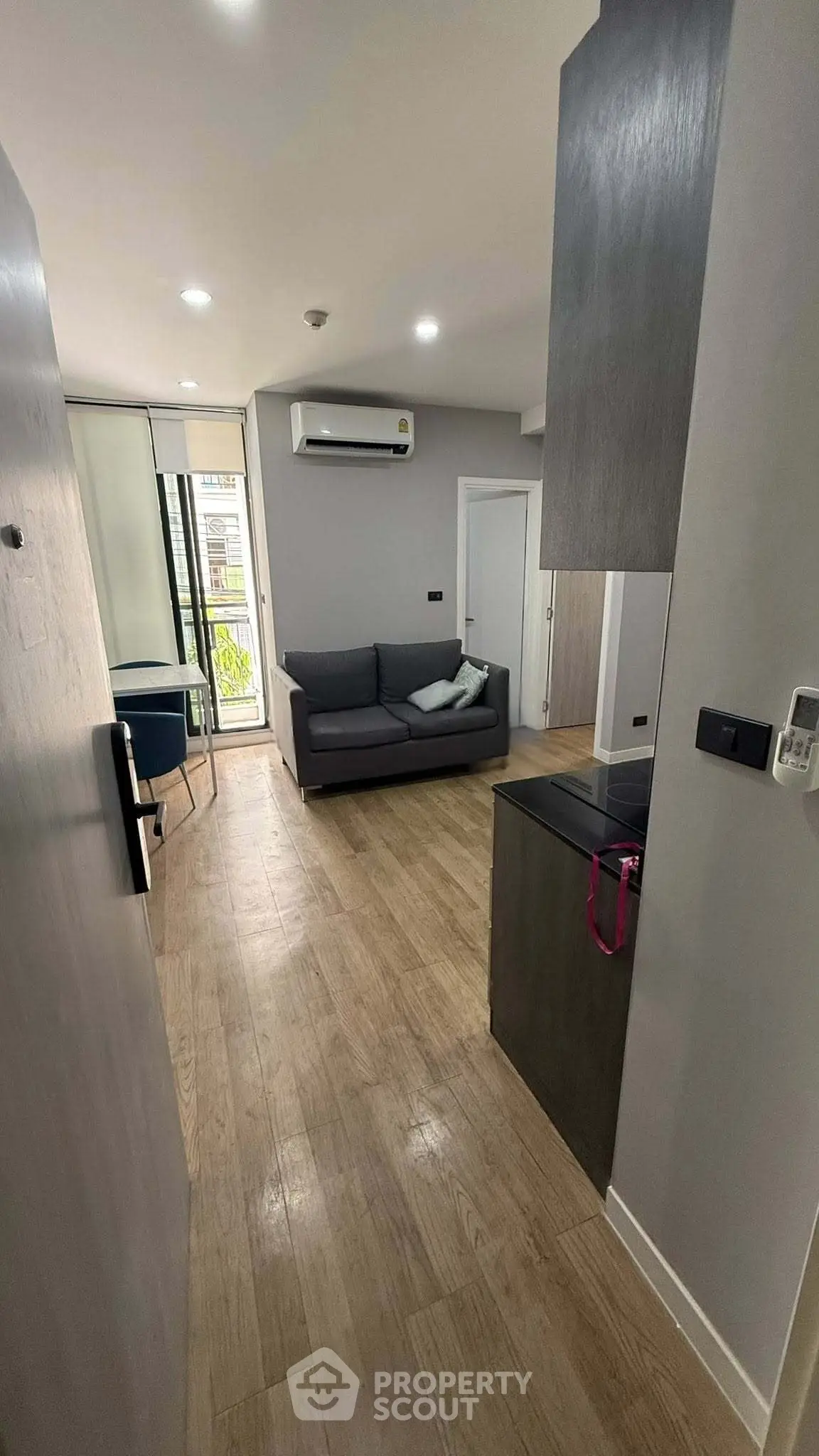 Modern living room with sleek design and wooden flooring, featuring a cozy sofa and air conditioning.