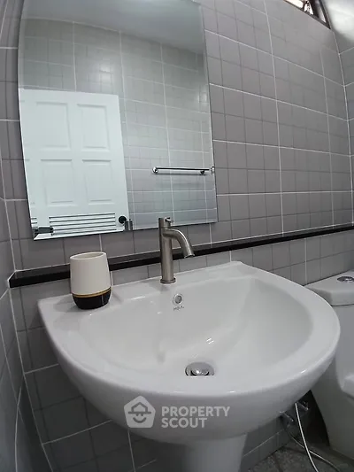 Modern bathroom with sleek sink and mirror in stylish tiled setting.