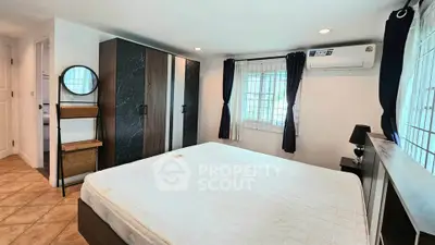 Spacious bedroom with modern wardrobe and air conditioning, featuring natural light and tiled flooring.
