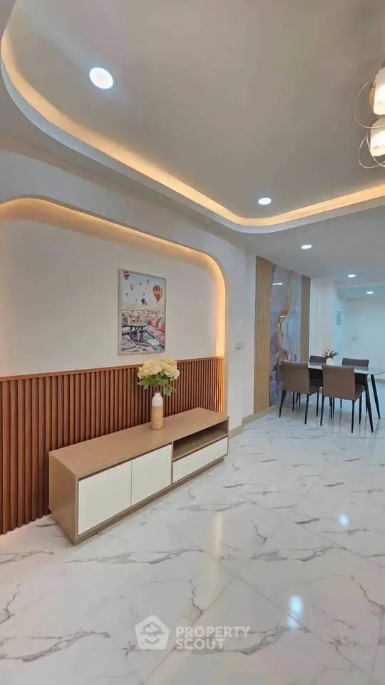 Modern living room with elegant lighting and marble flooring, featuring a stylish dining area and contemporary decor.
