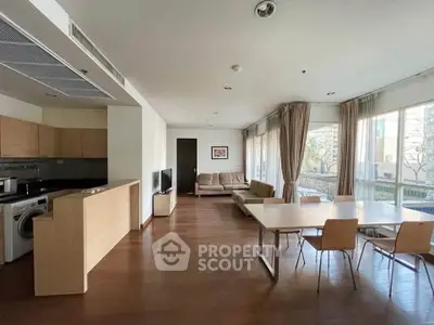Spacious open-plan living room with modern kitchen and dining area, featuring large windows and natural light.