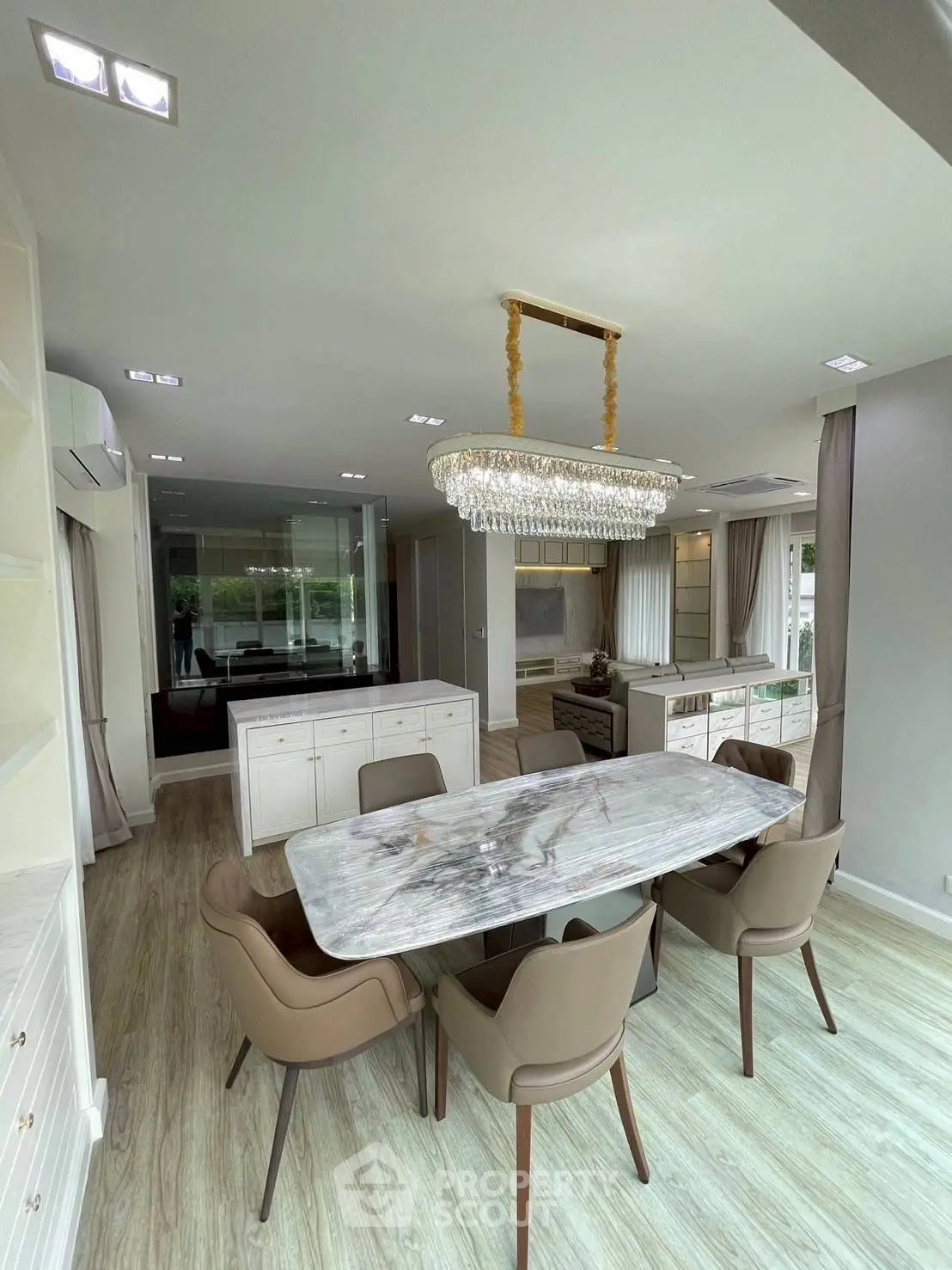 Luxurious dining area with elegant chandelier and marble table in modern open-plan home.
