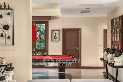 Stylish living room with a red pool table and artistic decor, perfect for entertainment and relaxation.