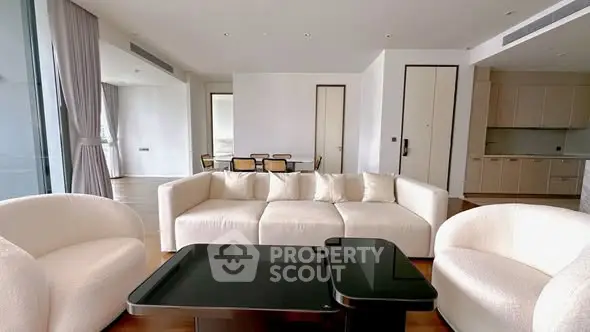 Luxurious modern living room with elegant white furniture and open kitchen layout.