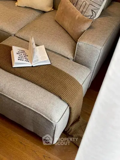 Cozy living room with stylish gray sofa and open book on a textured throw blanket.