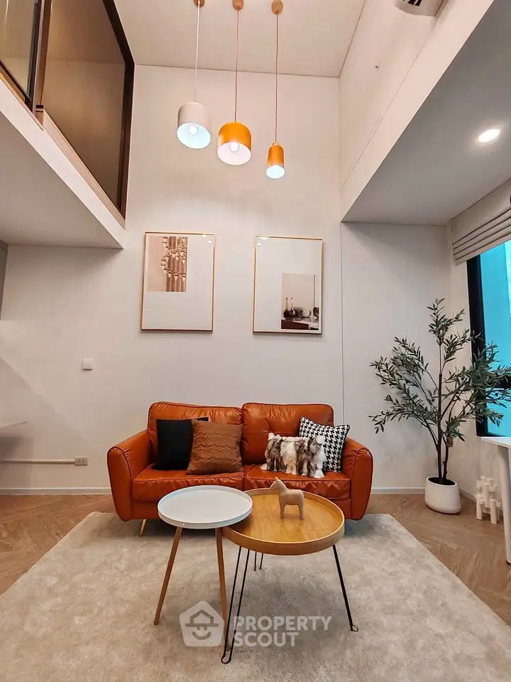 Modern living room with high ceiling, stylish lighting, and cozy leather sofa.