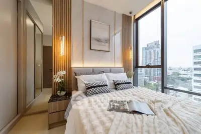 Luxurious bedroom with floor-to-ceiling windows offering stunning city views, elegant decor, and cozy bedding.