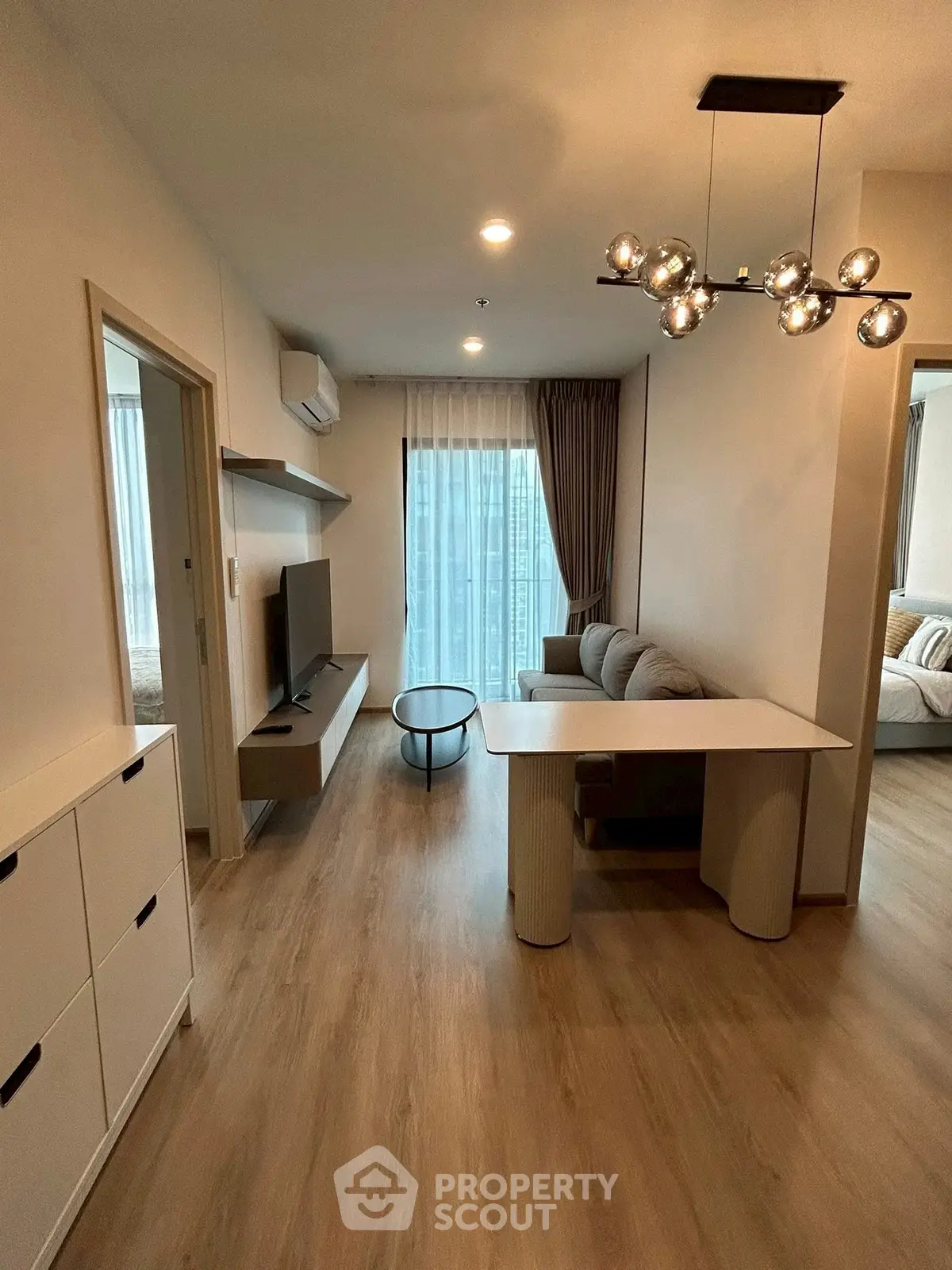 Modern living room with stylish lighting and cozy seating area, featuring a sleek TV setup and natural light.