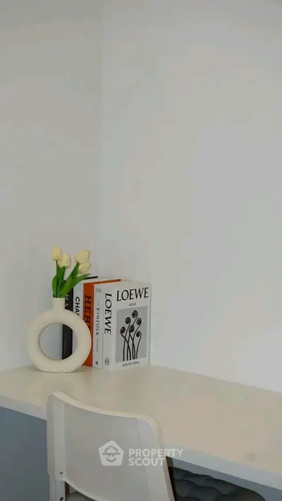Minimalist study corner with white desk, chair, and decorative books.