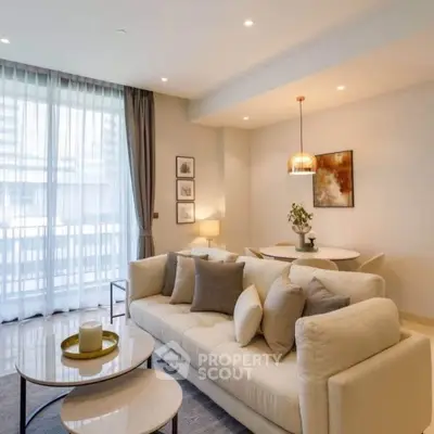 Elegant living room with modern decor, cozy sofa, and natural light from large windows.