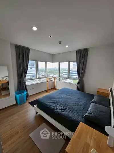 Spacious bedroom with large windows and modern decor in urban apartment