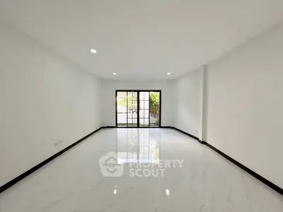 Spacious empty living room with large windows and glossy white flooring.