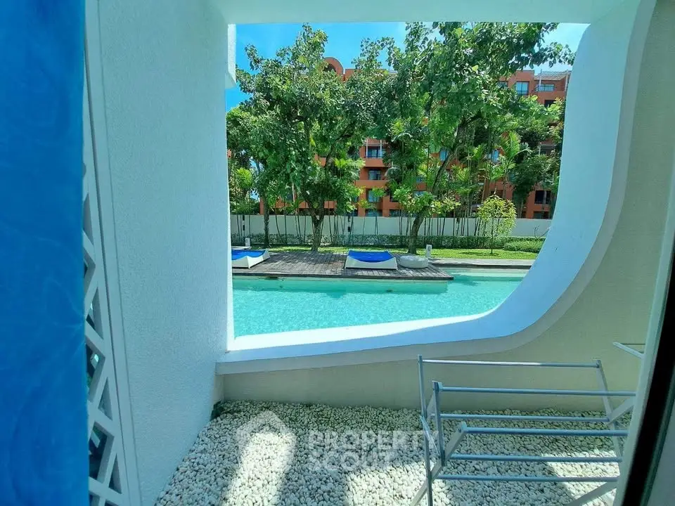 Luxurious poolside view from a modern apartment balcony with lush greenery.