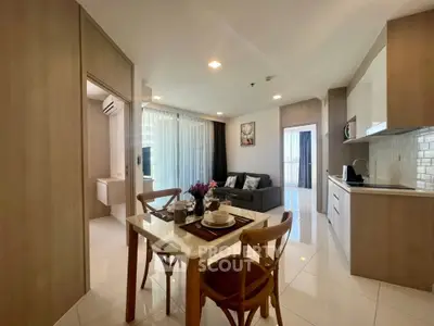 Modern open-plan living room with kitchen and dining area, featuring sleek design and natural light.