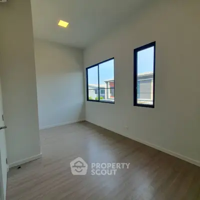 Bright and airy room with large windows and wooden flooring, perfect for a cozy bedroom or home office.