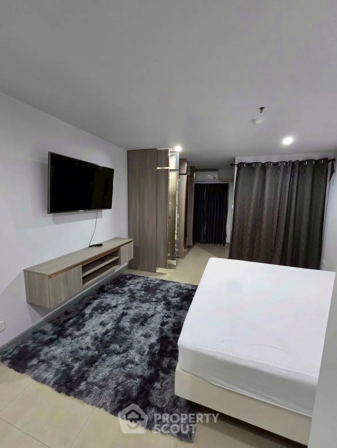 Modern bedroom with wall-mounted TV and plush carpet