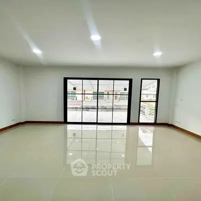 Spacious empty room with large windows and glossy tiled floor