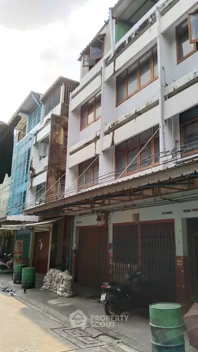 Charming urban building exterior with rustic charm and potential for renovation in a bustling neighborhood.