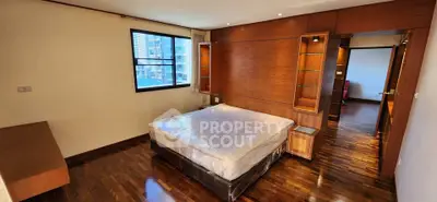 Spacious bedroom with wooden flooring and modern design in a high-rise apartment.