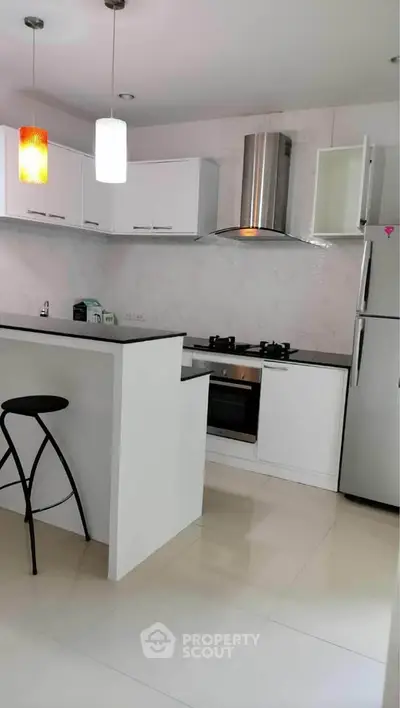 Modern kitchen with sleek white cabinets, gas stove, and breakfast bar seating.
