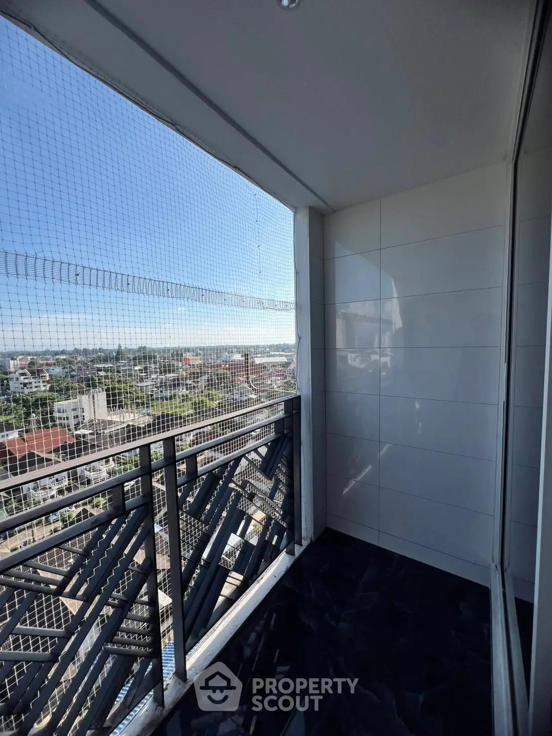 Spacious balcony with safety netting and panoramic city view, perfect for relaxation.