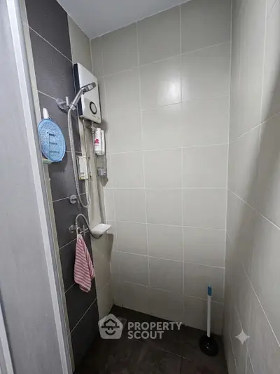 Compact bathroom with shower and tiled walls, featuring essential amenities.