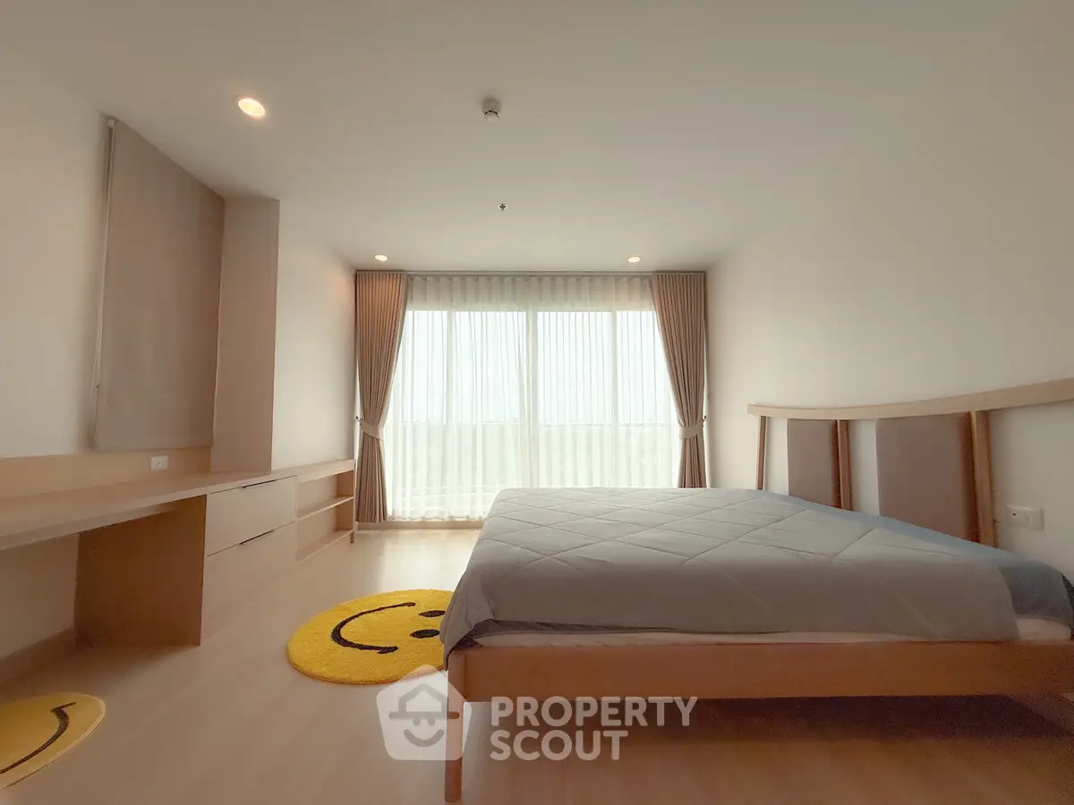 Spacious bedroom with modern decor and large window for natural light.