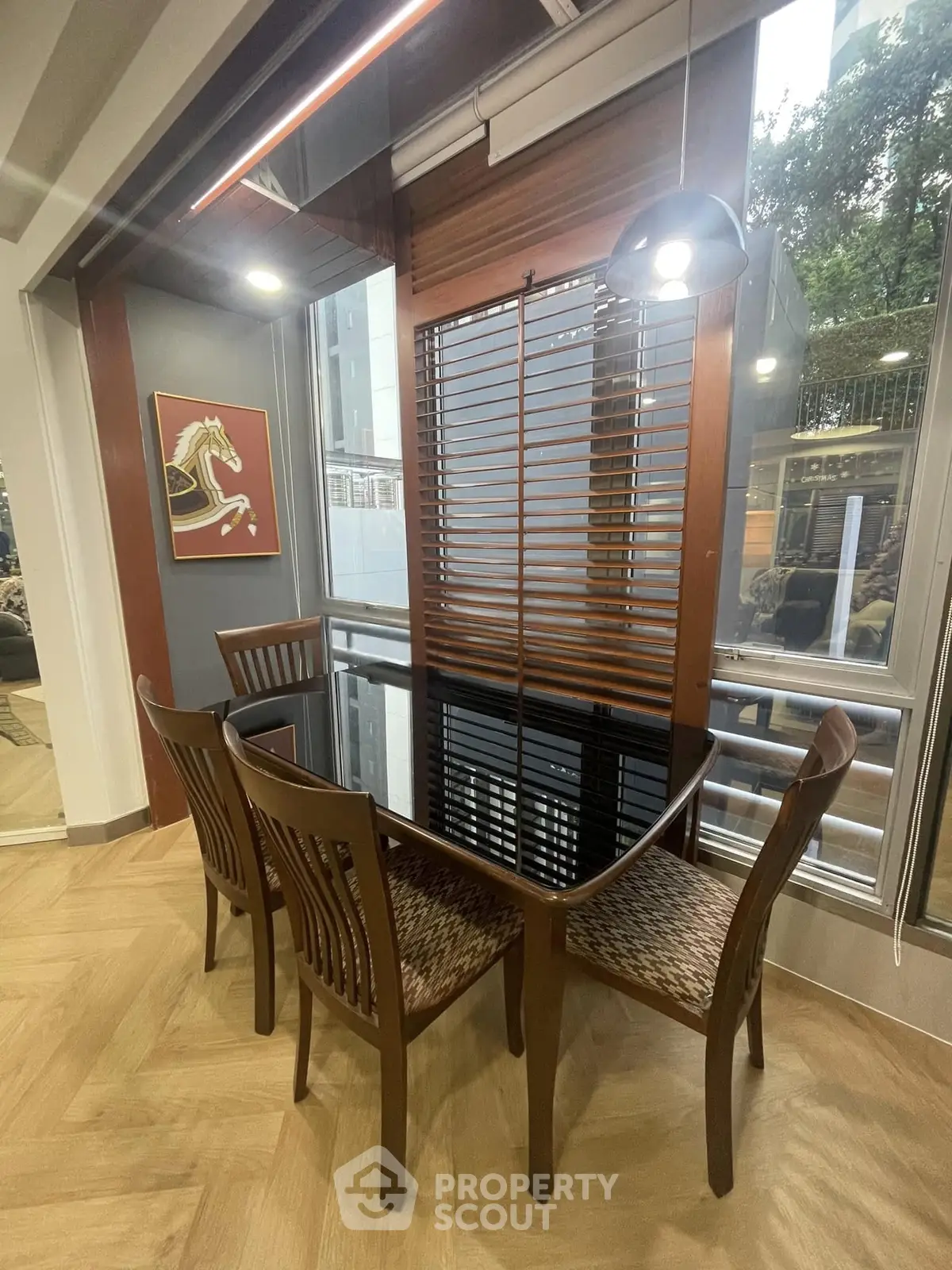 Elegant dining area with glass table and wooden chairs, featuring modern decor and large windows.