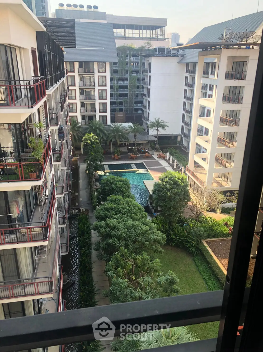 Luxurious apartment complex with lush gardens and a stunning pool view from the balcony.