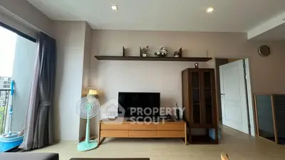 Modern living room with sleek TV stand, wall shelf, and stylish decor in a cozy apartment.