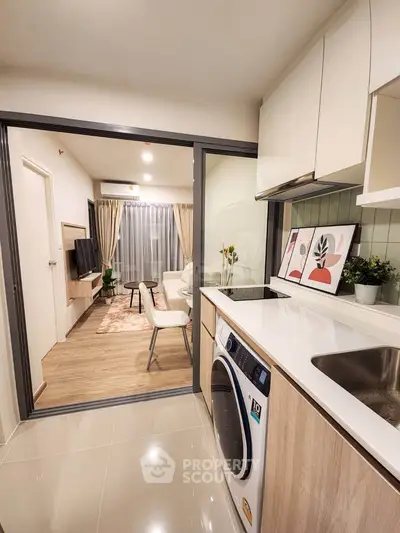 Modern open-layout kitchen with washing machine and view into stylish living room