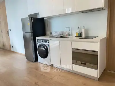 Modern compact kitchen with sleek appliances and wooden flooring in a stylish apartment.