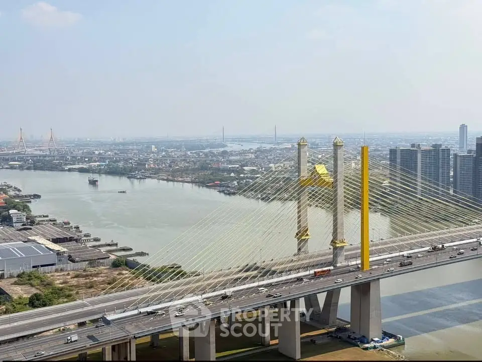 Stunning aerial view of a modern cable-stayed bridge over a river with cityscape backdrop.